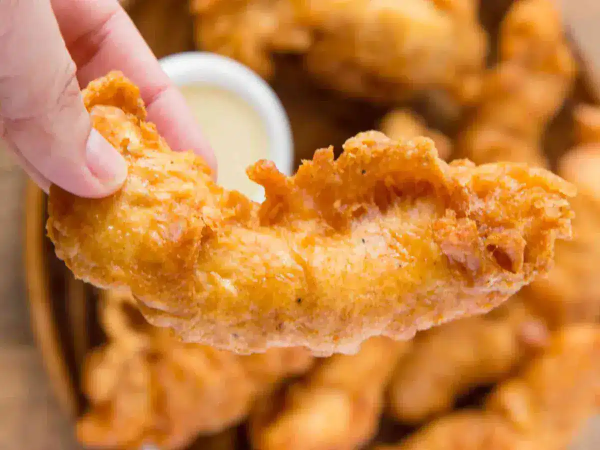 hand holding one chicken strip