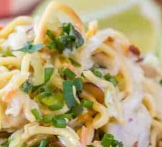 Ramen salad on a plate with 2 half limes.