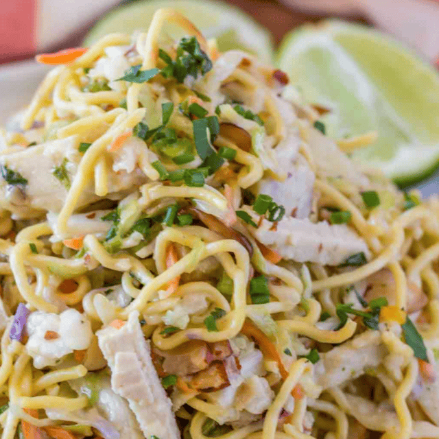 salad piled high on a plate and limes in the back