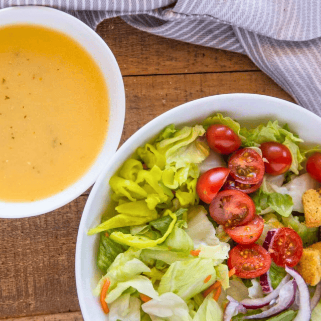 Bowl of salad dressing next to salad