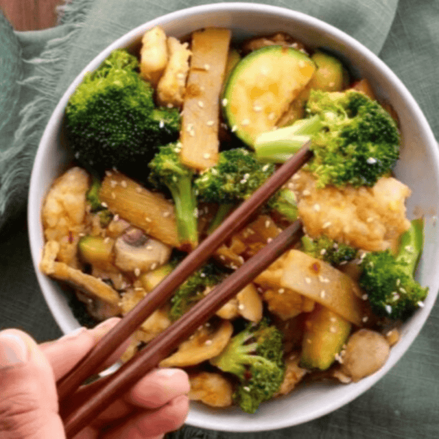 chopsticks grabbing chicken and broccoli from bowl