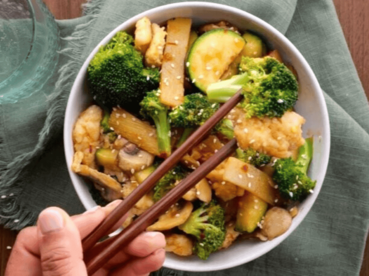 chopsticks grabbing chicken and broccoli from bowl