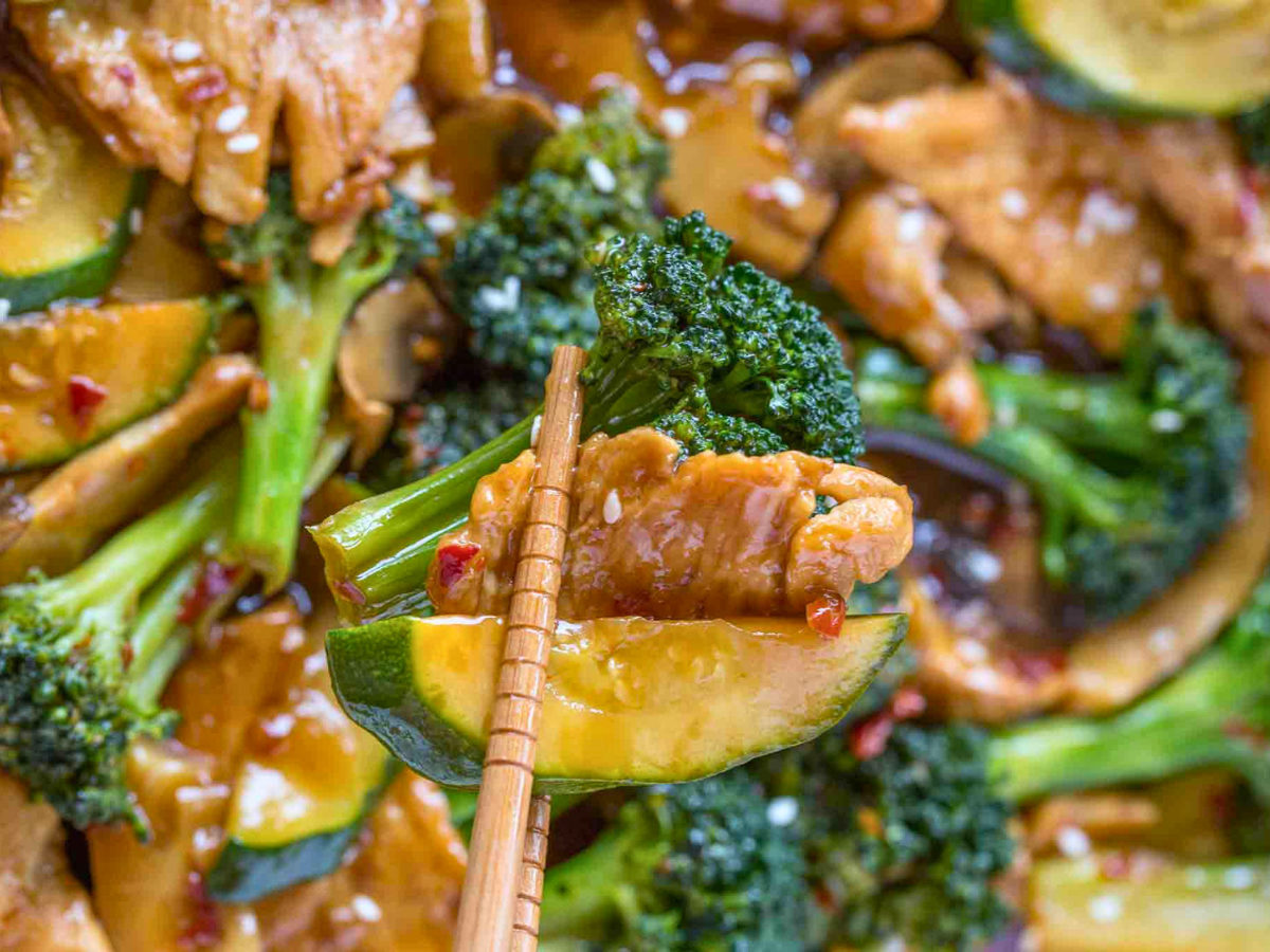 chopsticks grabbing chicken and broccoli from bowl
