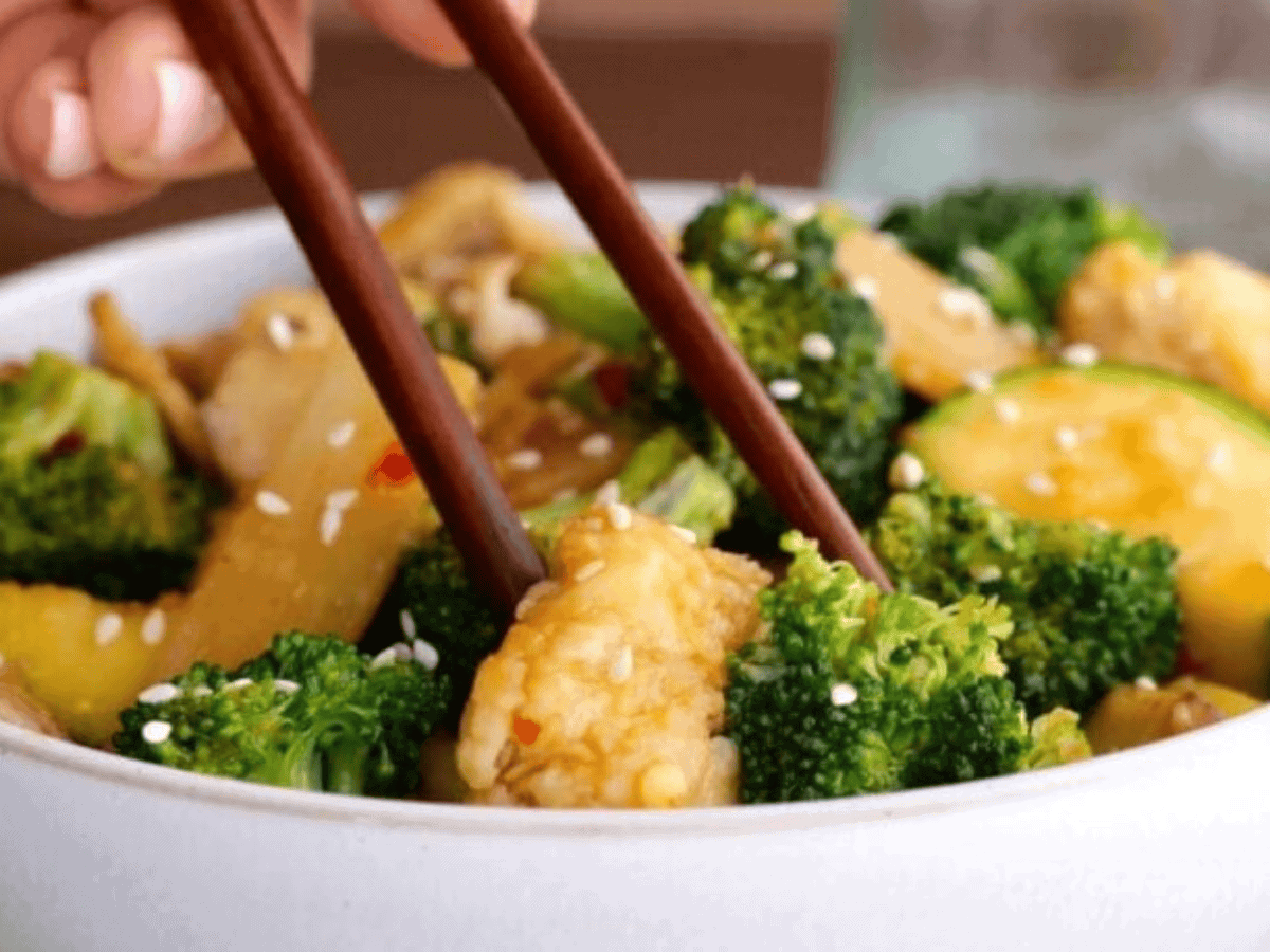 cooked spiced poultry, zucchini, and broccoli in between chopsticks