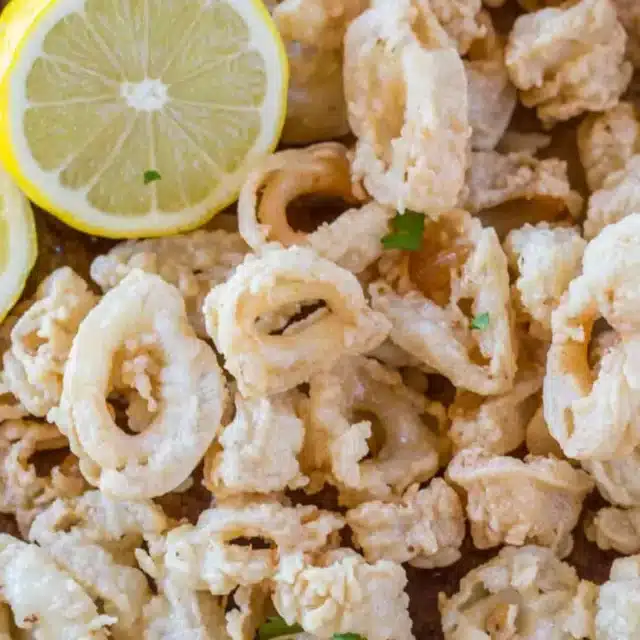 Closeup of fried squid on a baking sheet with a lemon on the side