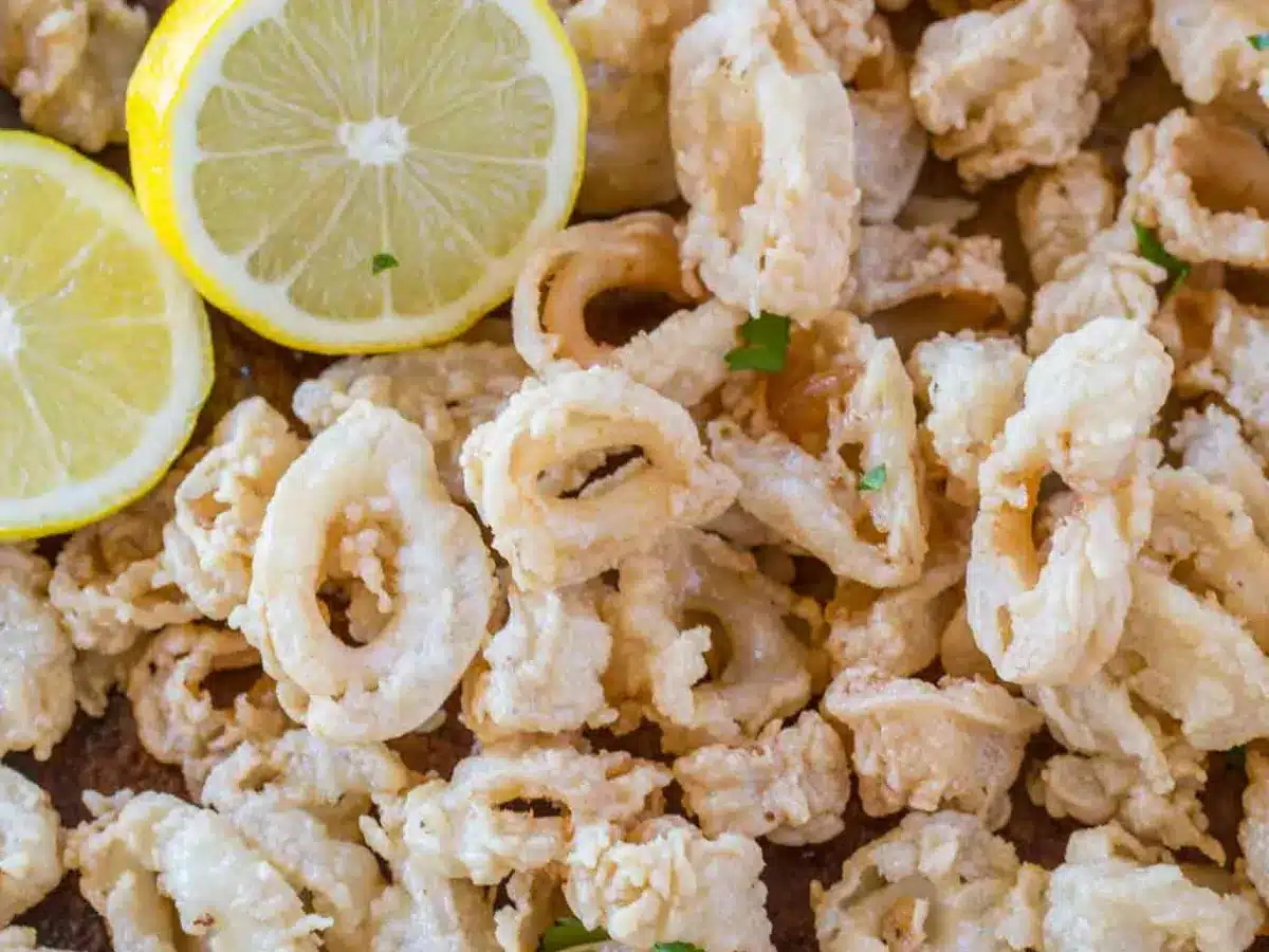 Closeup of fried squid on a baking sheet with a lemon on the side 