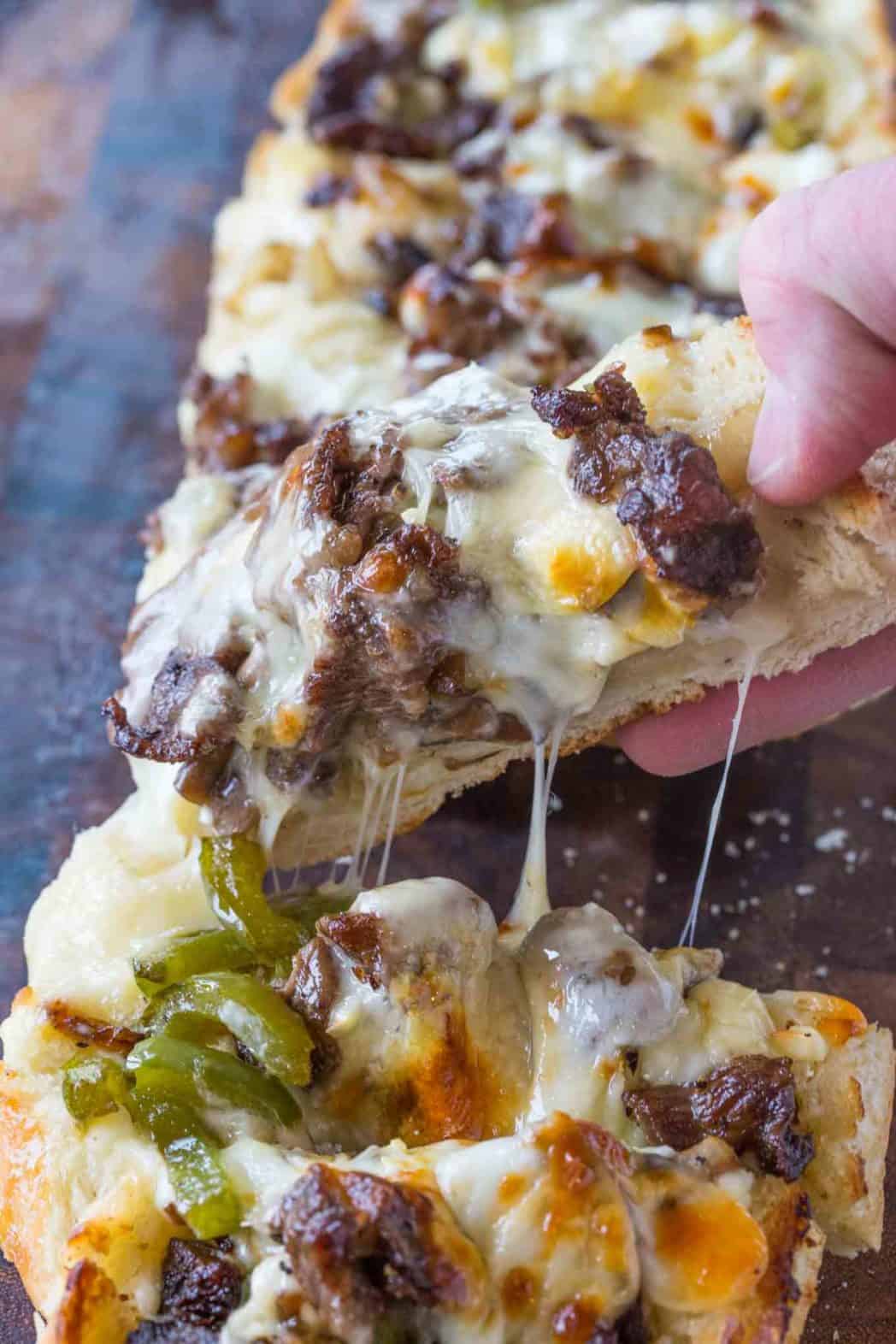 Philly Cheesesteak Cheesy Bread being lifted off cutting board