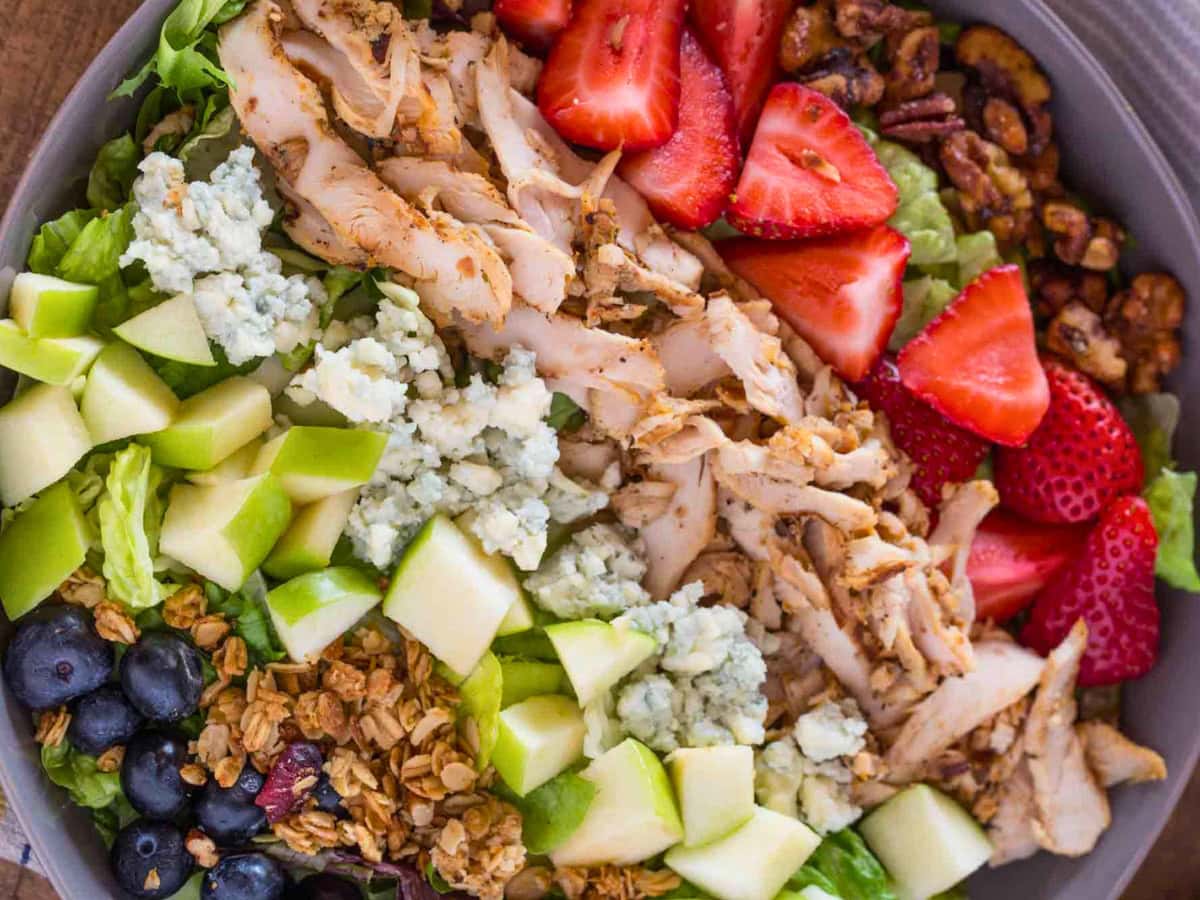 Salad from above with fruits, nuts, cheese, and chicken