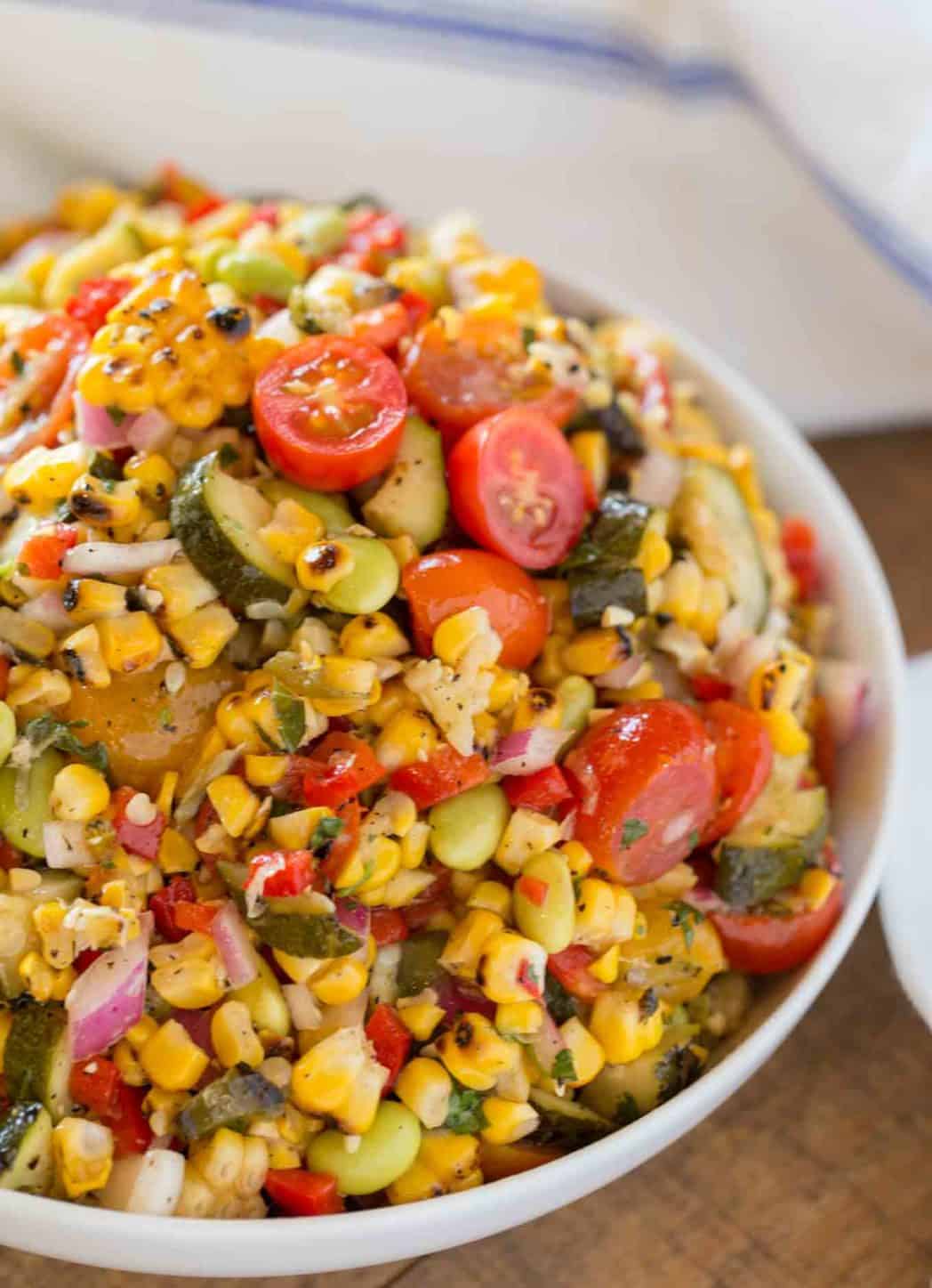 Corn and vegetable succotash served in a white bowl.