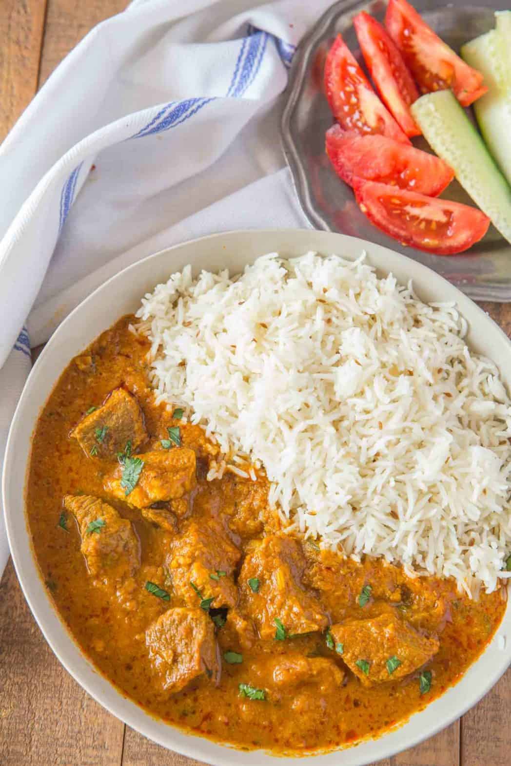 Bowl of rice and curry with vegetables on the side