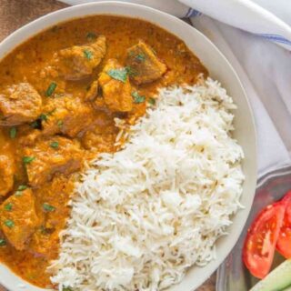 Curry in a bowl with tomatoes on the side.