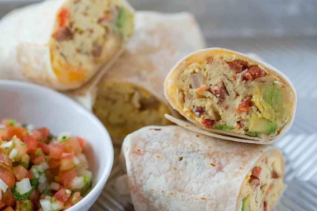 Halved burritos piled on plate with pico de gallo