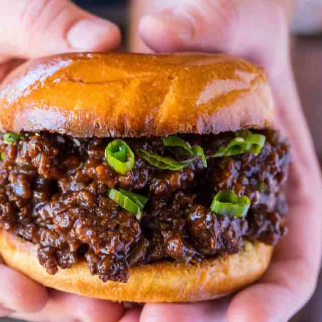 hands holding ground beef sandwich