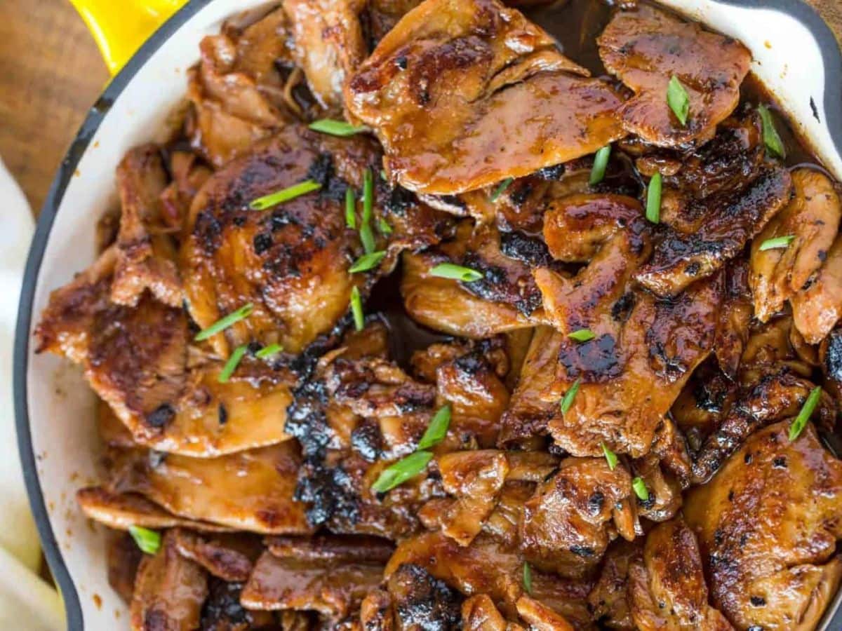 Chicken in a white pot with green onions for garnish.