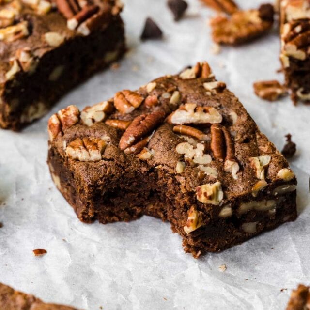 Brownies squares on parchment with bite taken
