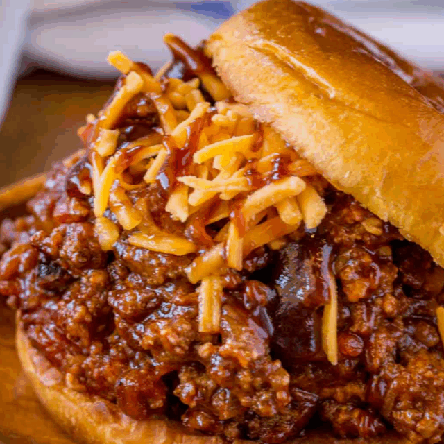 beef mixture topped with cheese overflowing off of bun