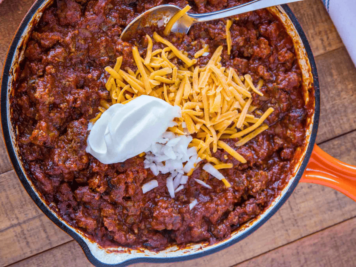 ground beef, beans, cheese and sour cream in a skillet with a spoon