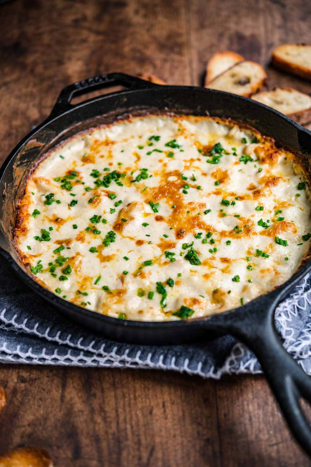 Garlic Shrimp Dip shrimp in skillet after baking with melted cheese and parsley garnish
