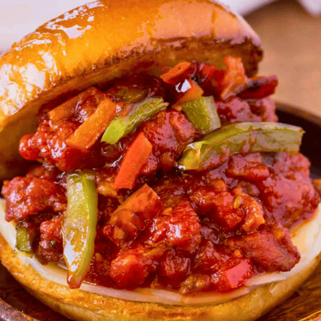 Seasoned pork with veggies in between two hamburger buns