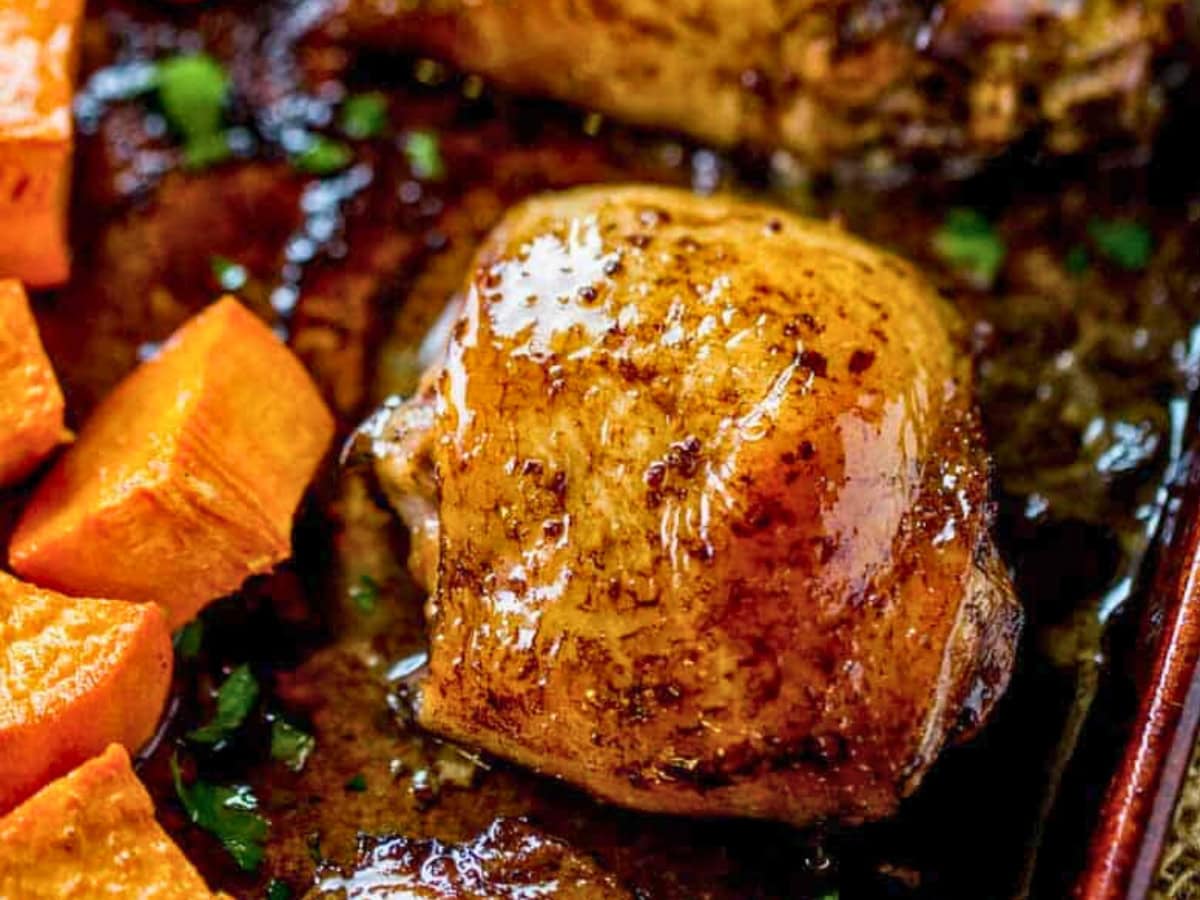 Roasted chicken thigh and sweet potatoes on a baking sheet