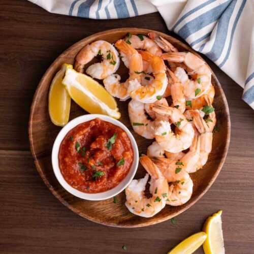 Shrimp Cocktail on serving plate with cocktail sauce and lemon wedges