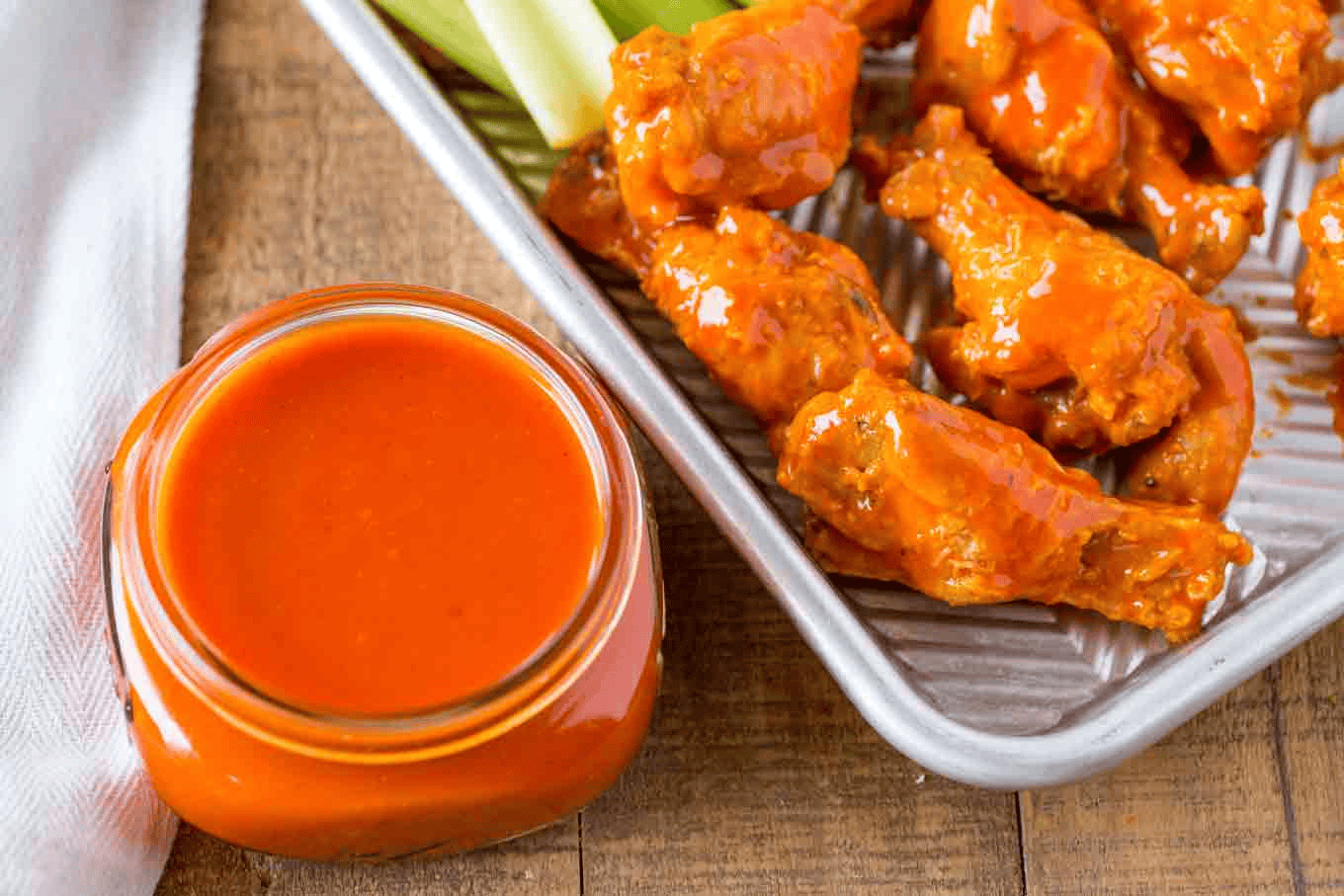 Sauce in a jar next to chicken wings