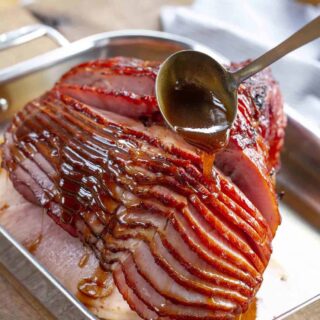Baked Ham with Brown Sugar Glaze made with brown sugar, orange juice, honey, and spices is the PERFECT sweet and savory holiday dinner, and bakes in only 90 minutes! Ladling brown sugar glaze over ham