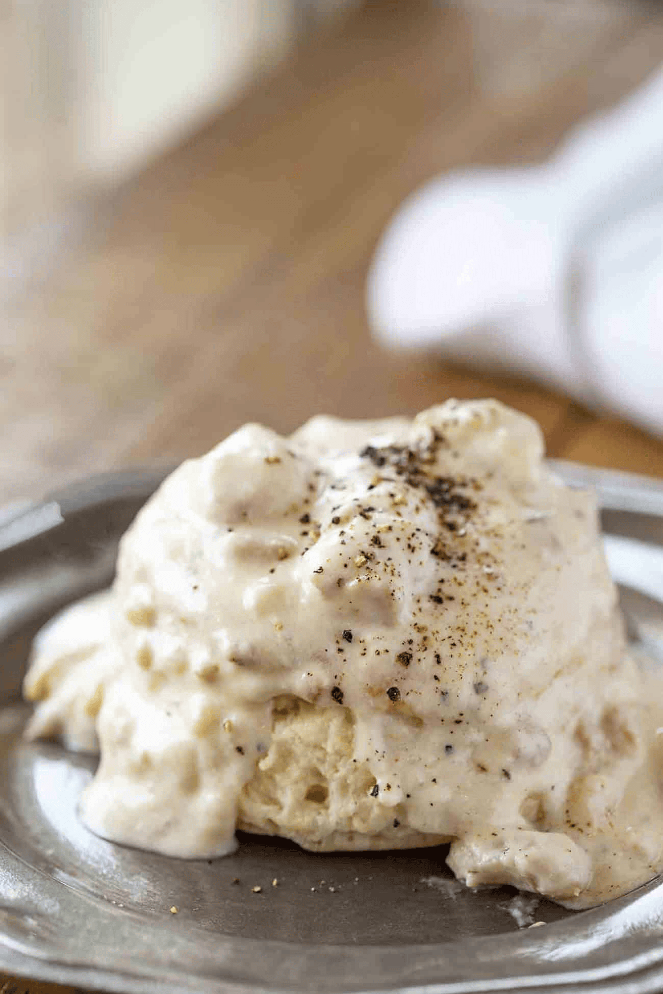 Gravy on top of a biscuit with black pepper on top