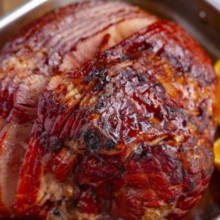 Baked Ham with Brown Sugar Glaze made with brown sugar, orange juice, honey, and spices is the PERFECT sweet and savory holiday dinner, and bakes in only 90 minutes! #ham #bakedham #brownsugar #christmas #easy #recipe #dinner #glazed #bonein #spiral Baked ham with glaze in pan.