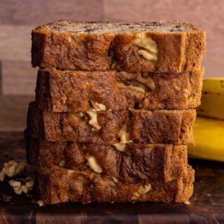 Banana Nut Bread sliced and stacked on board with bananas