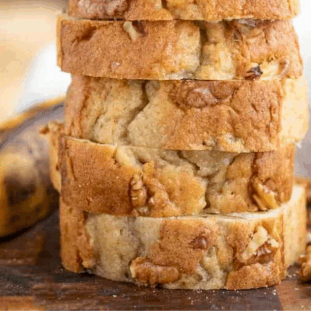 stacked slices of bread on a wooden board with a banana on the side