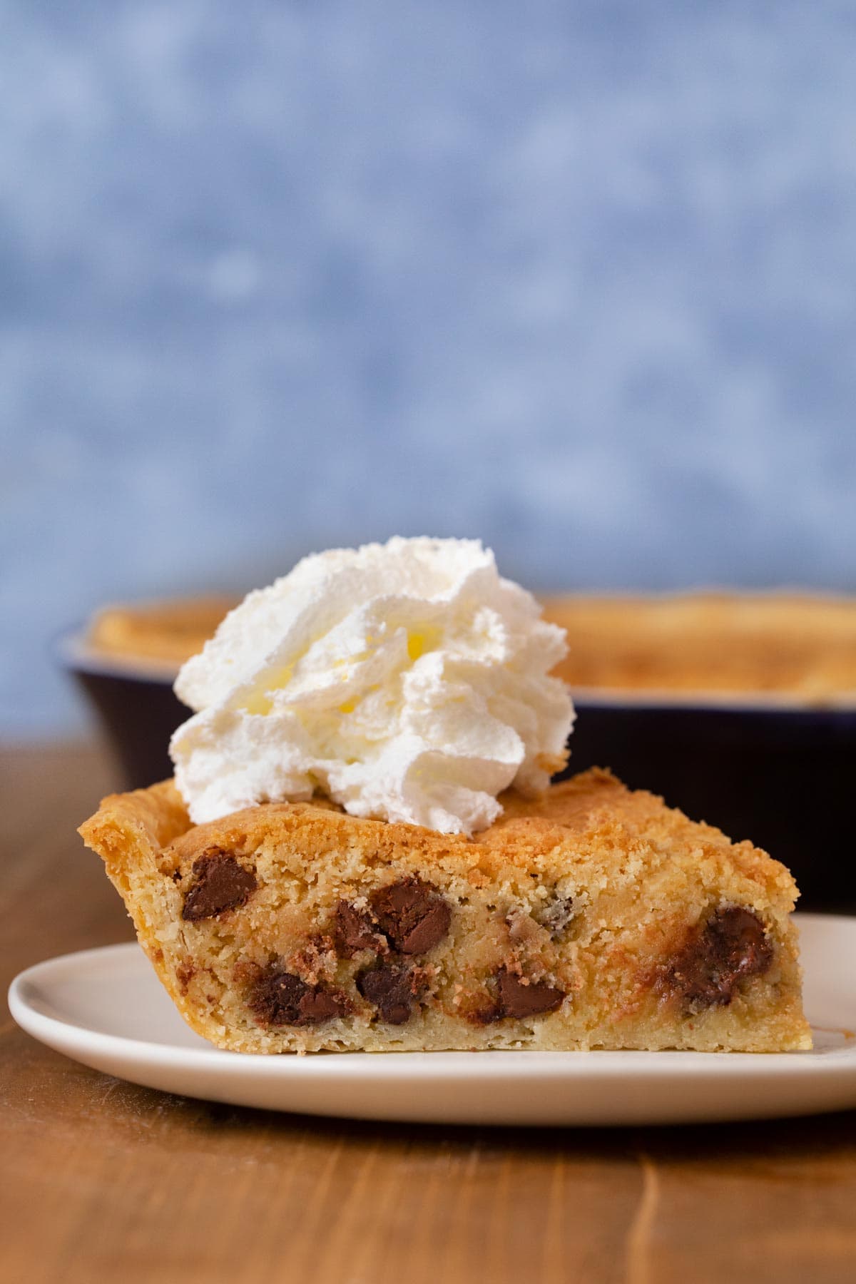 Chocolate Chip Cookie Pie slice on plate with whipped cream