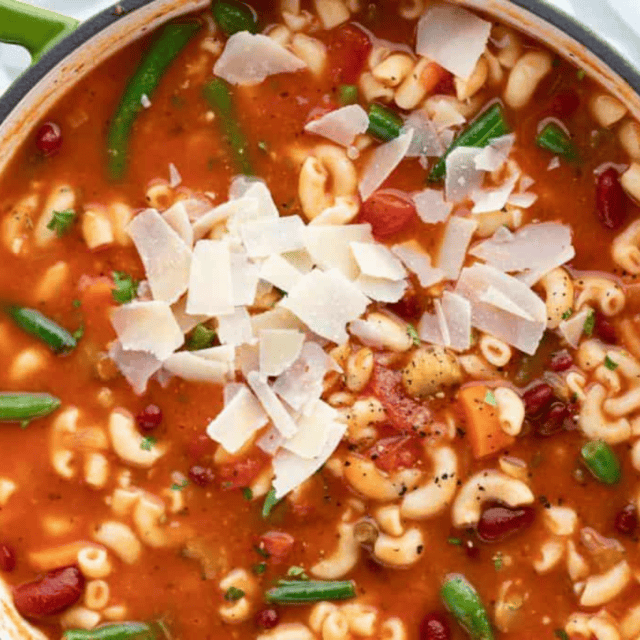 soup with veggies and noodles in a pot. topped with Parmesan.
