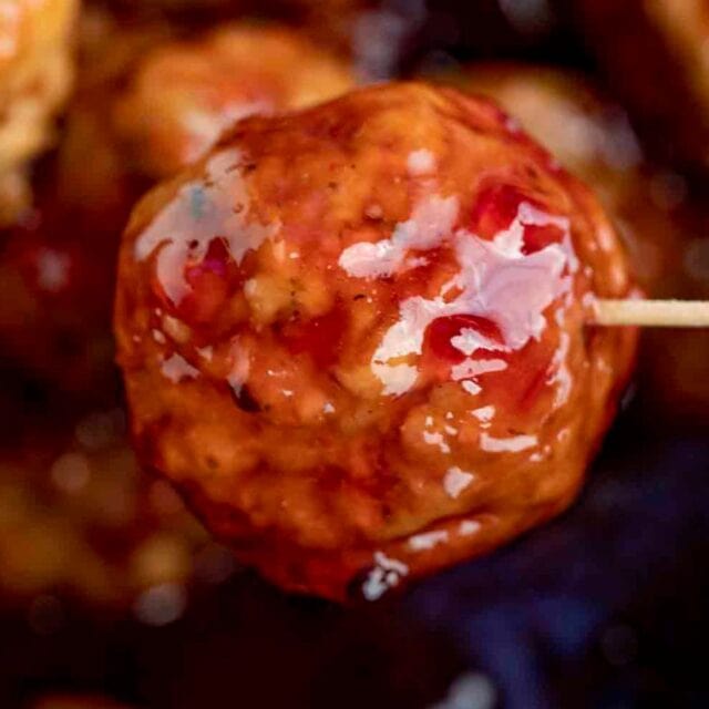 Close up of meatball with sauce on a toothpick.