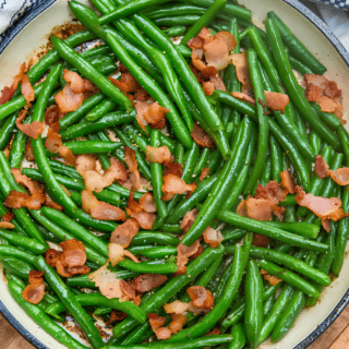 long slender green veggies with cooked bacon in skillet