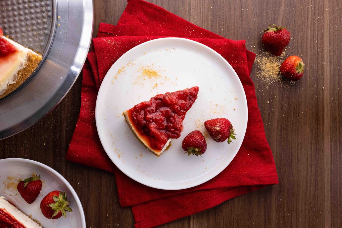 New York Cheesecake is the PERFECT sweet, creamy dessert made from cream cheese, sugar, eggs, and vanilla, baked into a graham cracker crust. New York Cheesecake slice on plate with strawberry topping