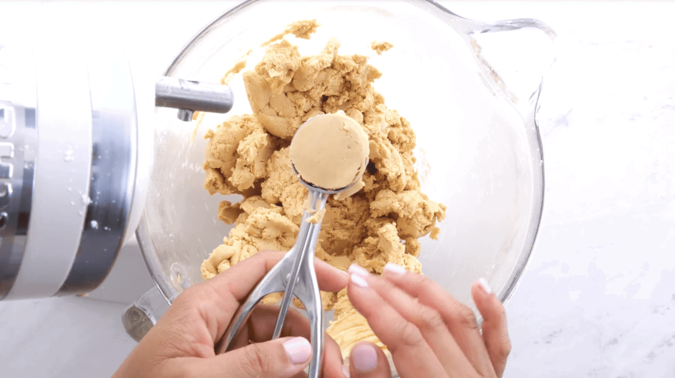 Scooping peanut butter dough from a mixing bowl