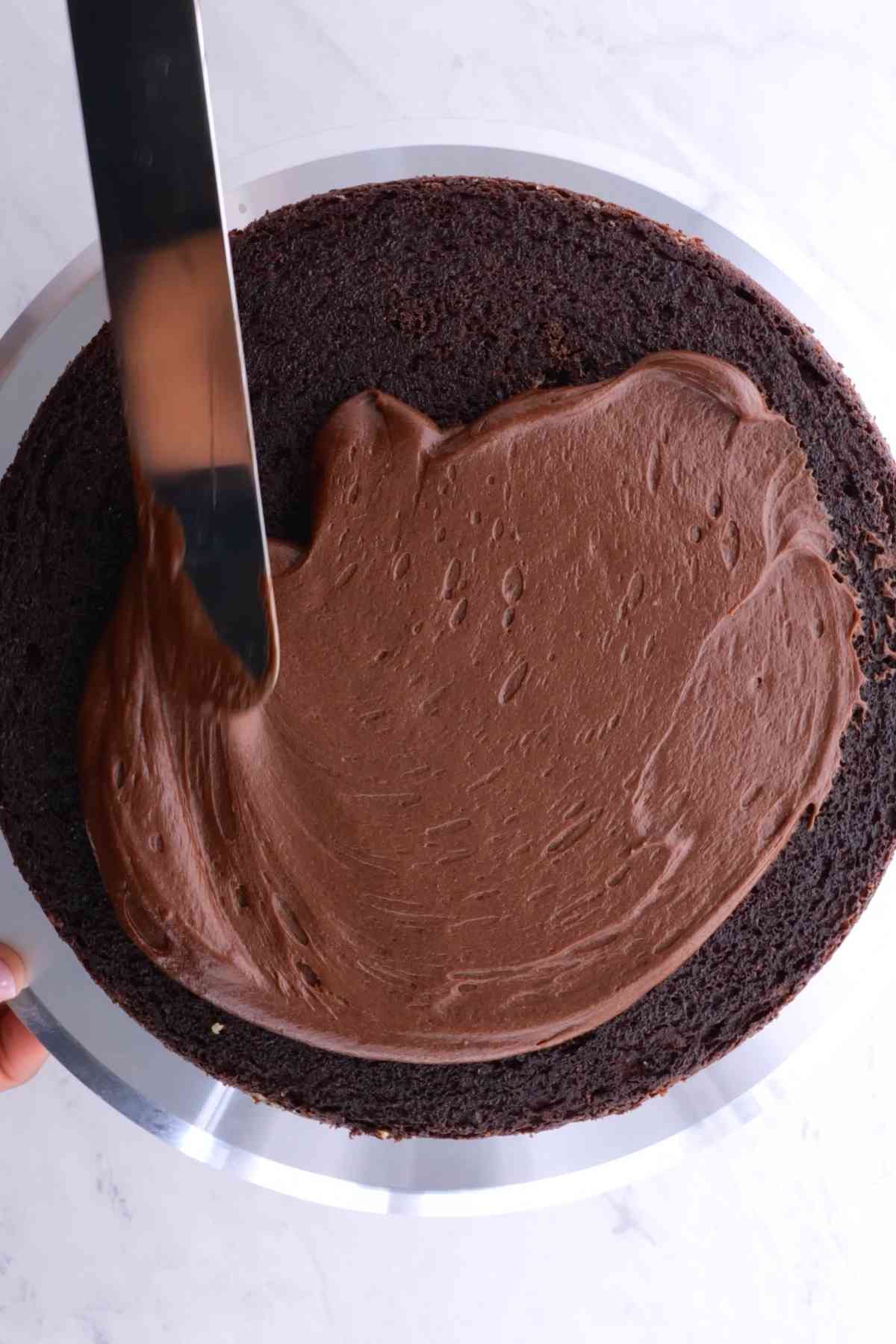 Chocolate Frosting being spread on chocolate cake