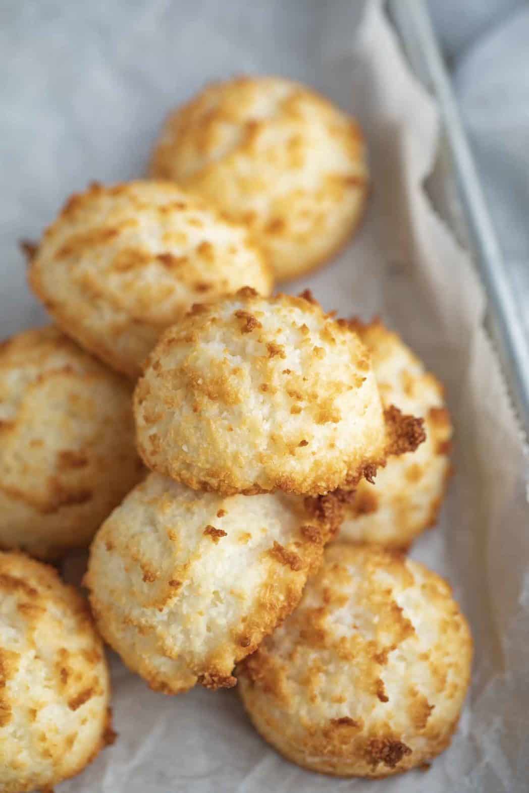 Sweet cookies piled on a parchment lined sheet