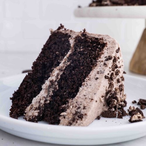 slice of dark cake with a fluffy layer in between and on top with cookie crumbs