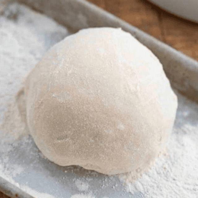 Flour on dough in a ball on baking sheet