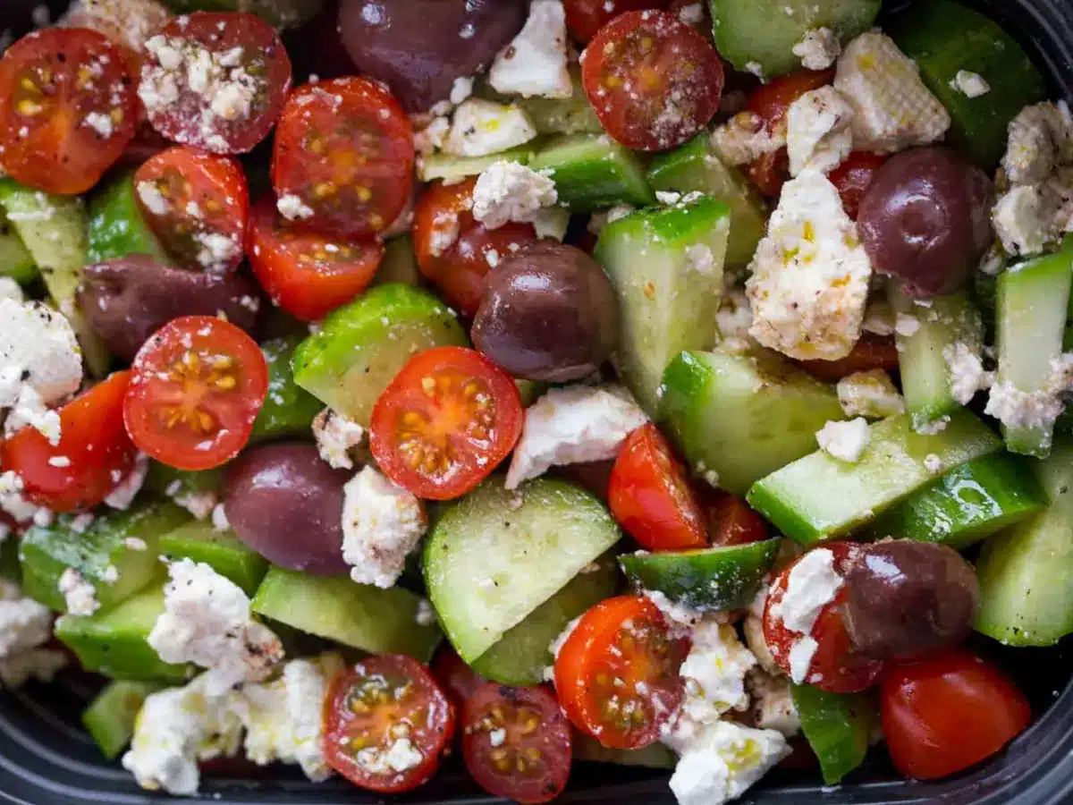 close up of tomatoes, cucumbers, olives and feta cheese in salad