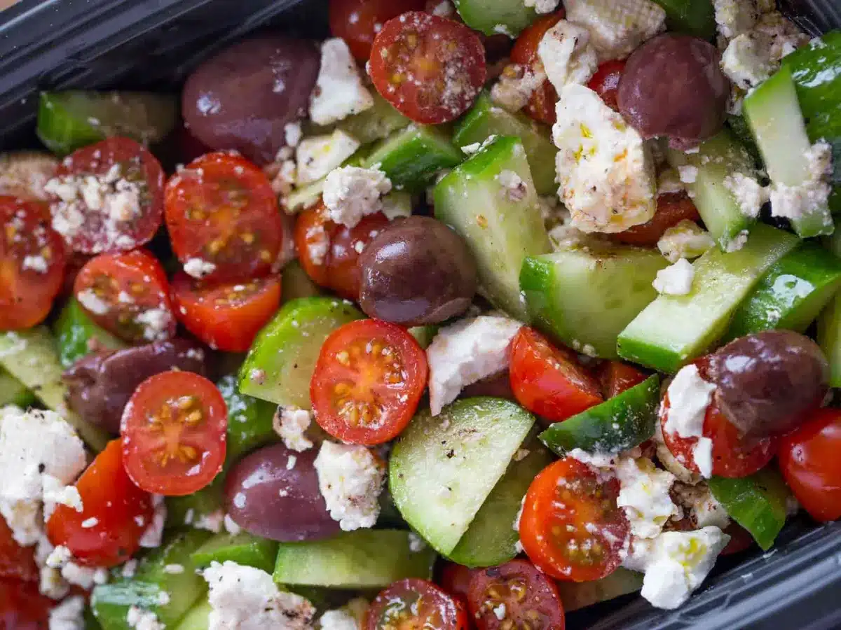 close up of tomato, cucumber and feta salad in container