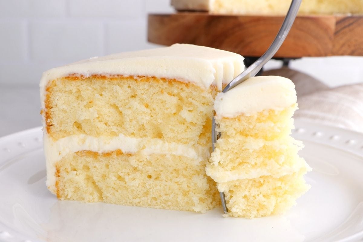 Classic Buttercream Frosting slice of vanilla cake on plate with fork