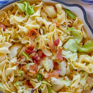 Egg pasta with bacon and cabbage in a white pan