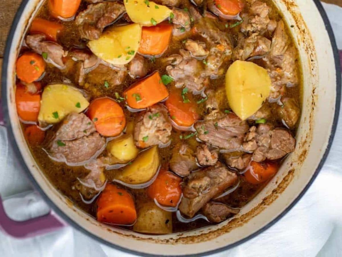 Stew in a large pot with lamb, carrots and potatoes.