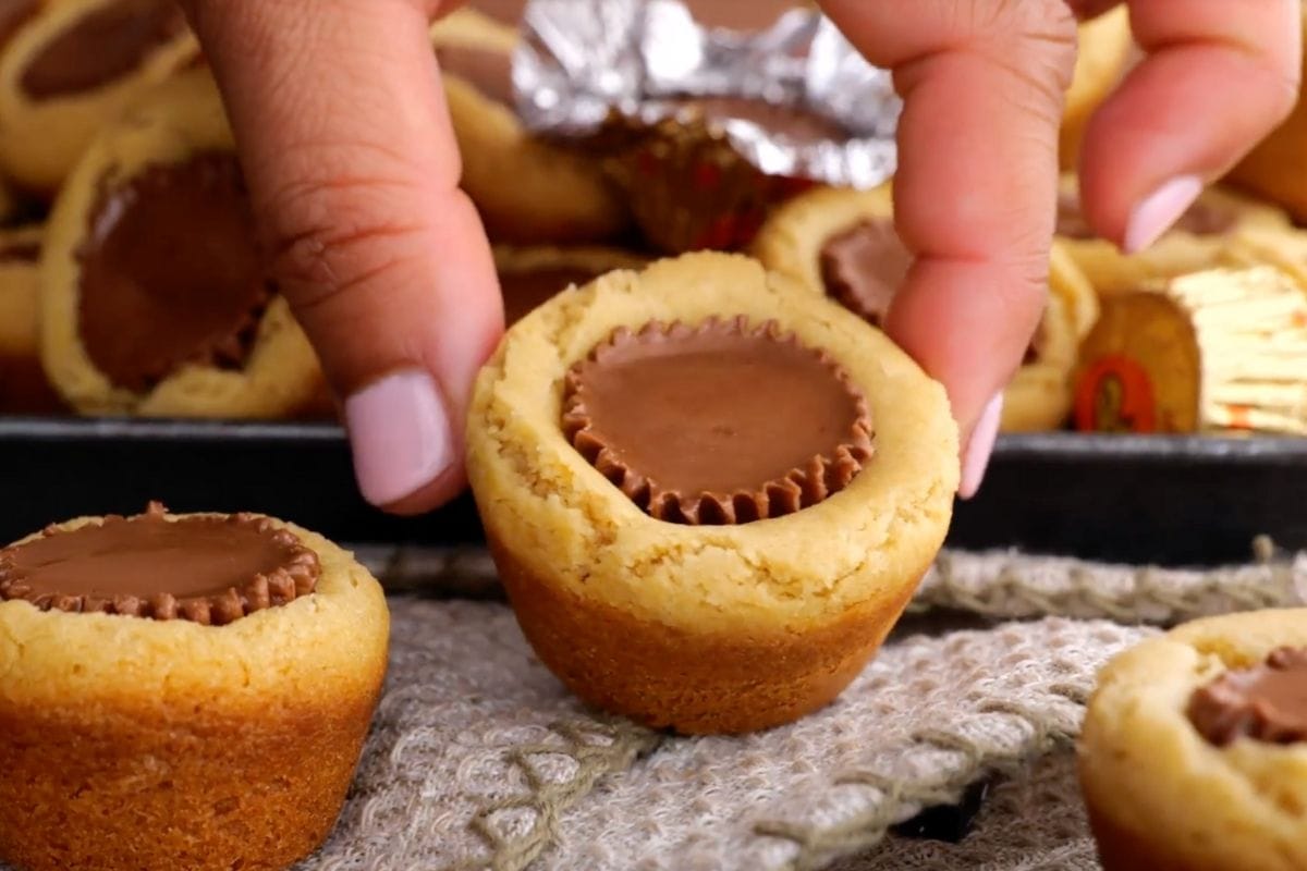 Peanut Butter Cup Cookies on serving plate and hand picking one up