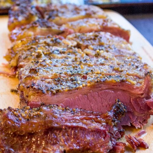 Cooked beef on cutting board with some slices cut.