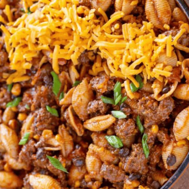 meat, pasta, veggies in a skillet topped with cheese