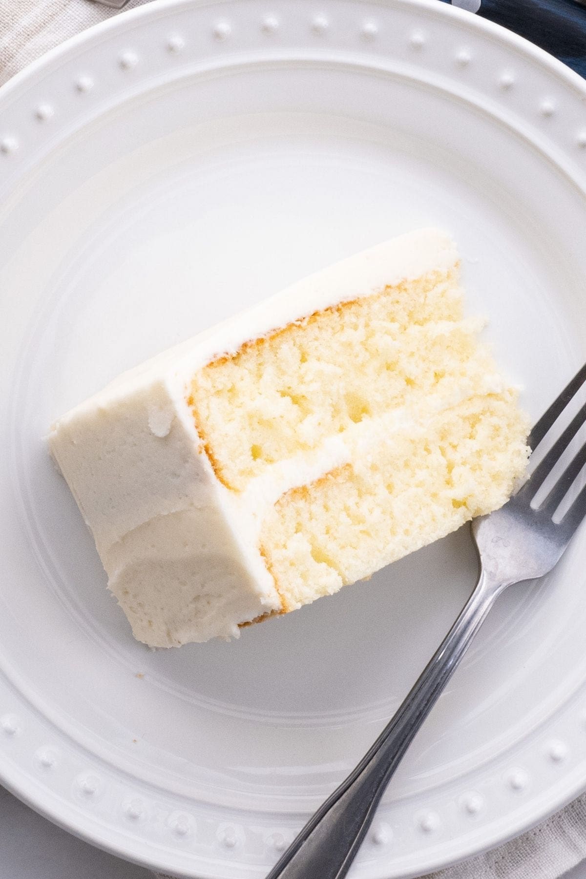 Classic Buttercream Frosting slice of vanilla cake on plate with fork